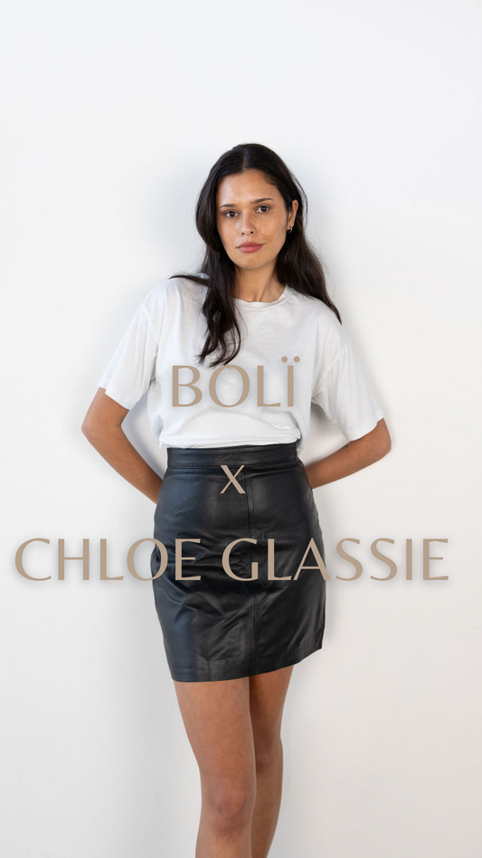 Chloe Glassie stands in a white tee and black leather boli skirt