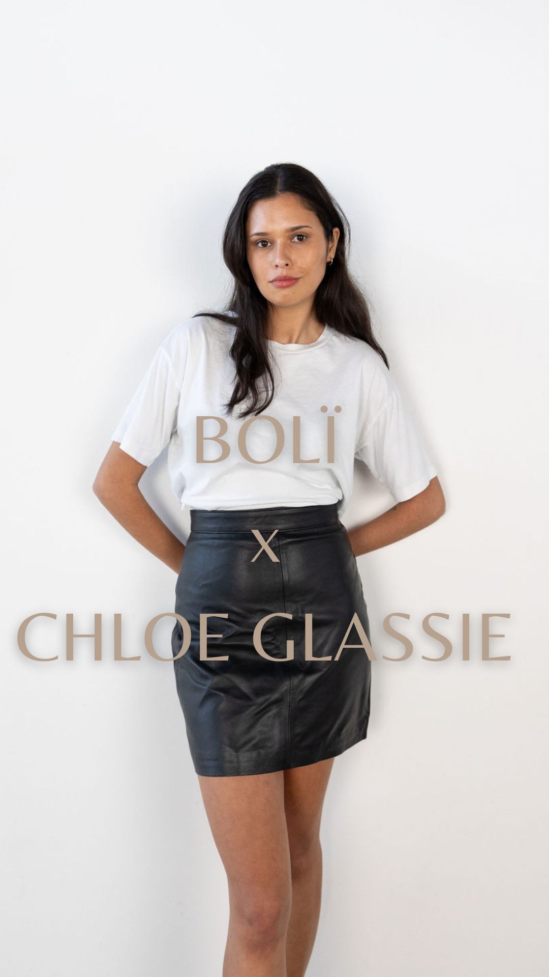 Chloe Glassie stands in a white tee and black leather boli skirt 